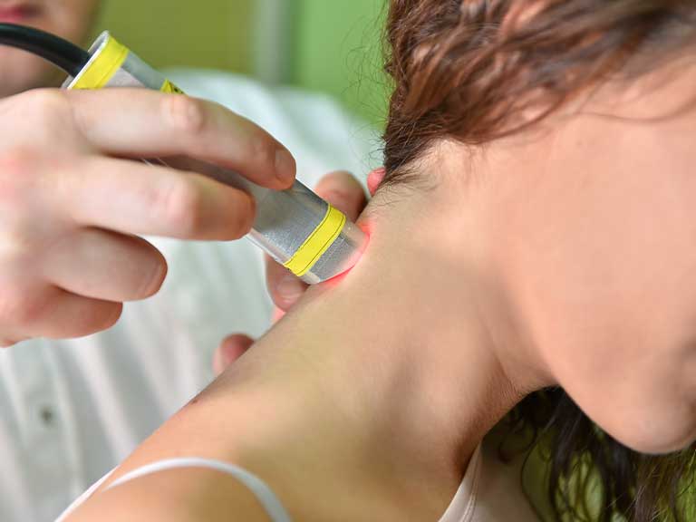 Patient suffering from neck pain receiving laser therapy